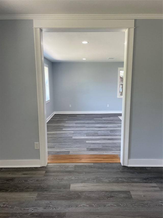 spare room with baseboards, crown molding, and wood finished floors