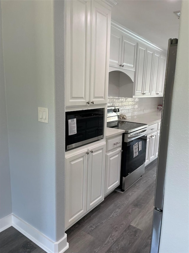 kitchen with light countertops, backsplash, white cabinets, dark wood-type flooring, and appliances with stainless steel finishes
