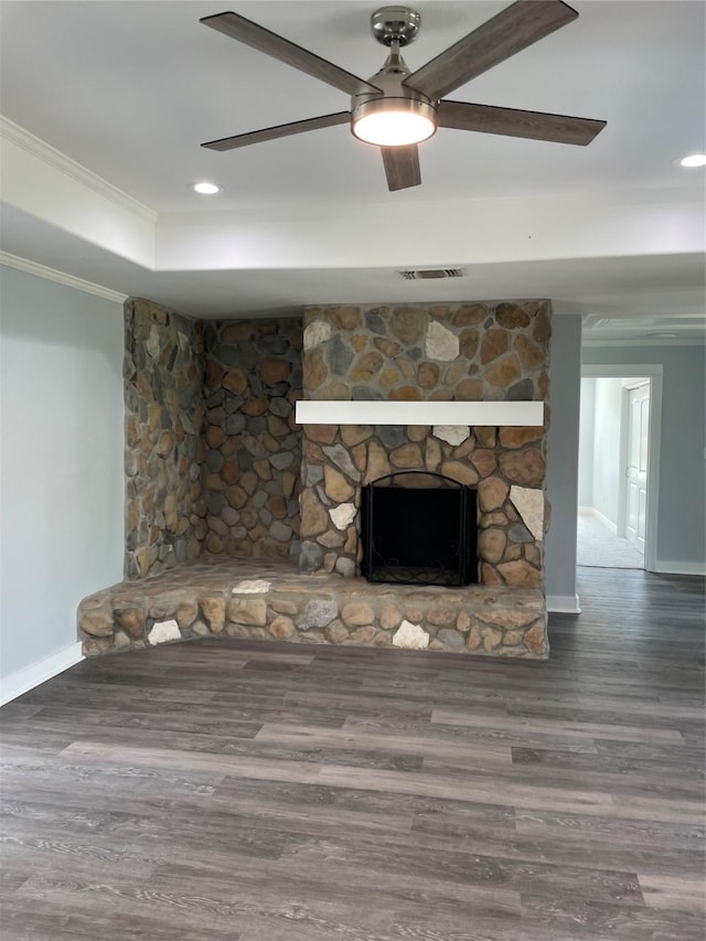 unfurnished living room featuring crown molding, baseboards, a stone fireplace, and wood finished floors