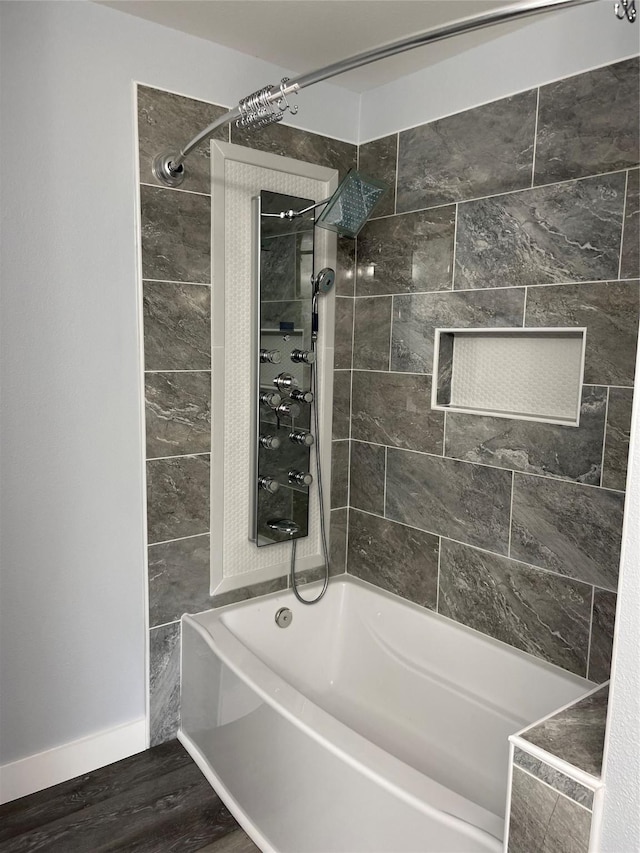 bathroom with bathtub / shower combination, baseboards, and wood finished floors