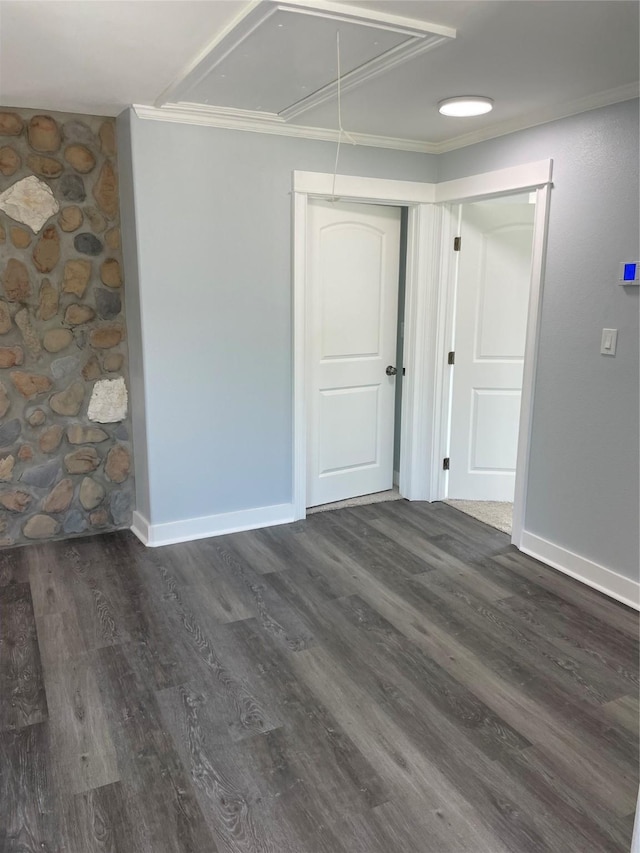 unfurnished room with wood finished floors, attic access, baseboards, and ornamental molding