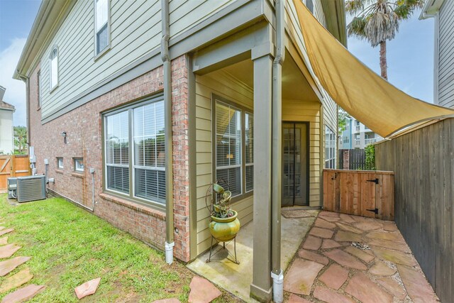 1301 Ketch Ct, League City, TX 77573 - view of exterior entry with brick siding, cooling unit, fence, and a patio