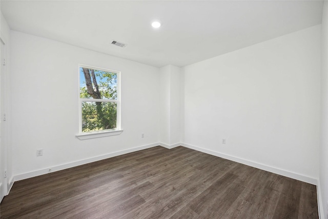 spare room featuring dark wood-style flooring, baseboards, visible vents, and recessed lighting