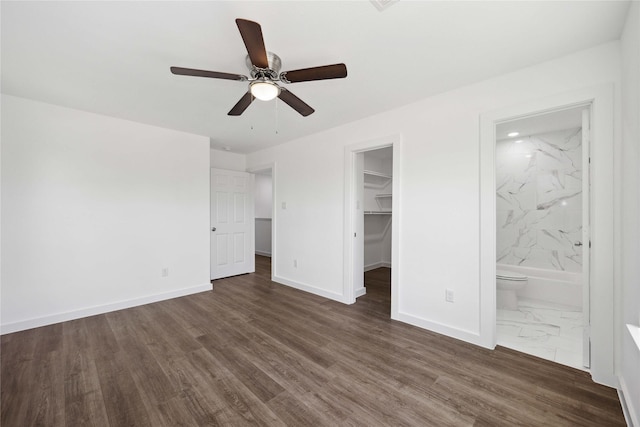 unfurnished bedroom featuring a closet, baseboards, a spacious closet, ceiling fan, and connected bathroom