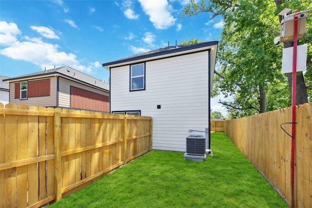 rear view of house featuring a yard, a fenced backyard, and central AC
