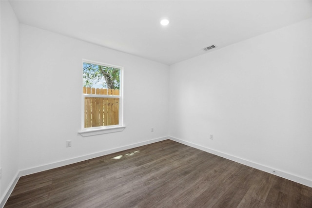 empty room featuring baseboards, dark wood-style floors, visible vents, and recessed lighting