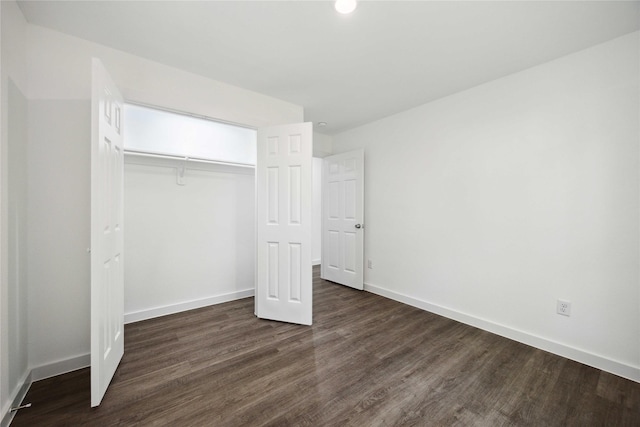 unfurnished bedroom with a closet, baseboards, and dark wood-style floors