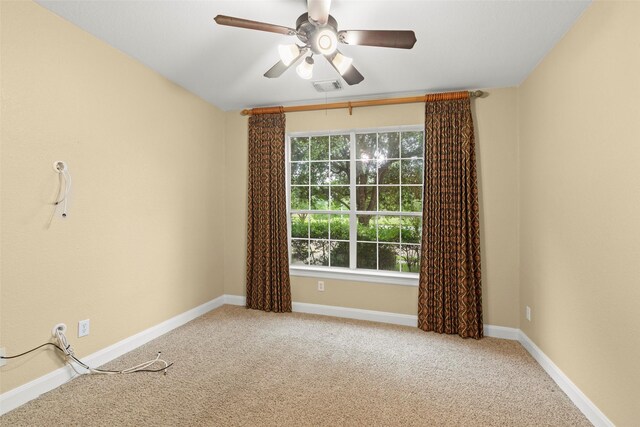 carpeted spare room featuring baseboards, ceiling fan, and visible vents