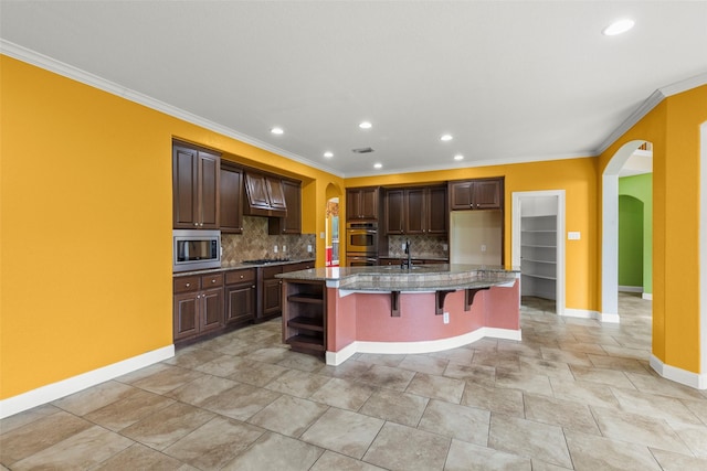 kitchen featuring decorative backsplash, appliances with stainless steel finishes, arched walkways, baseboards, and ornamental molding