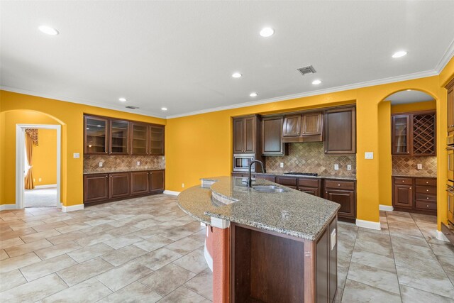 kitchen with visible vents, arched walkways, tasteful backsplash, appliances with stainless steel finishes, and a sink