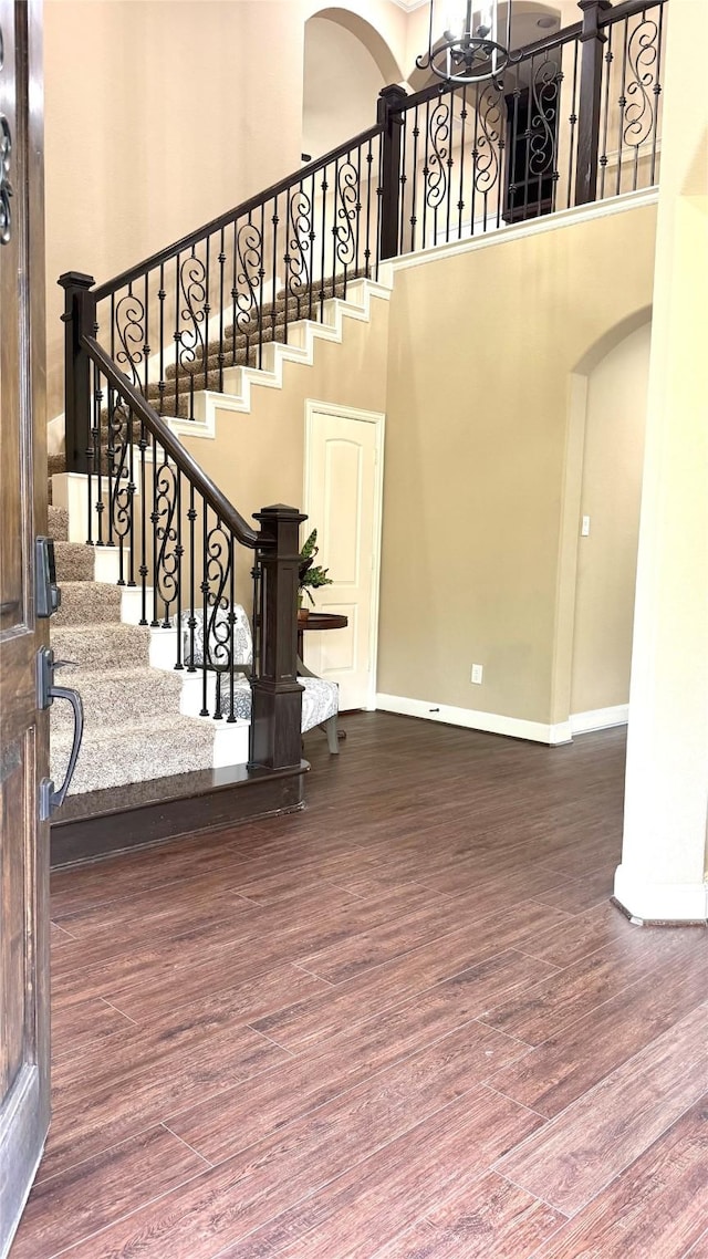 34315 E Short Leaf Pine Ct, Pinehurst, TX 77362 - stairway featuring an inviting chandelier, wood finished floors, a high ceiling, baseboards, and arched walkways