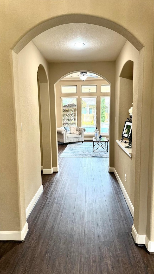 34315 E Short Leaf Pine Ct, Pinehurst, TX 77362 - corridor featuring dark wood-style flooring, baseboards, and arched walkways