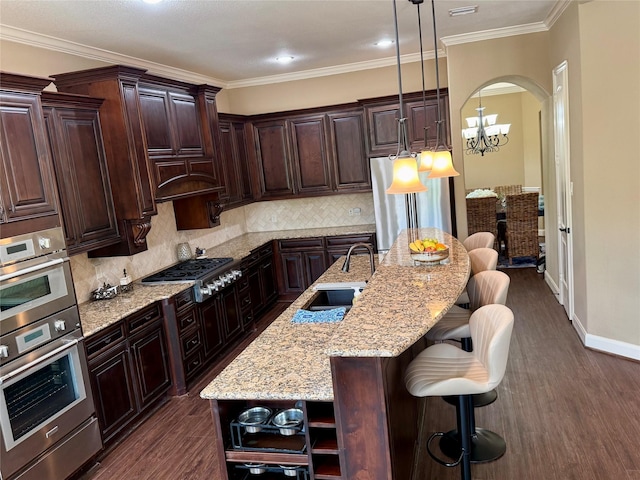 34315 E Short Leaf Pine Ct, Pinehurst, TX 77362 - kitchen with a breakfast bar area, dark wood-style flooring, a sink, stainless steel appliances, and an island with sink