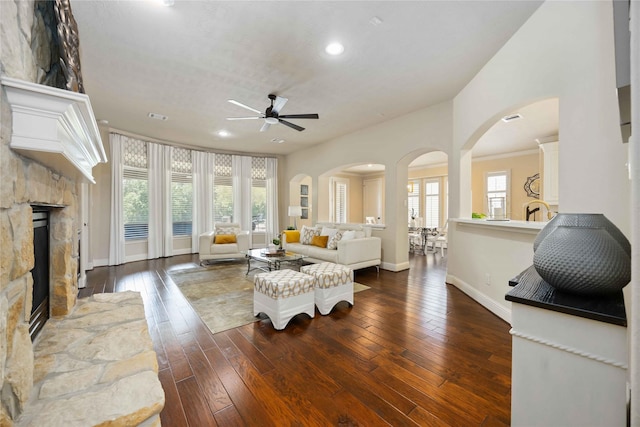 21207 Fairhaven Creek Dr, Cypress, TX 77433 - living room featuring recessed lighting, a stone fireplace, a ceiling fan, arched walkways, and dark wood-type flooring