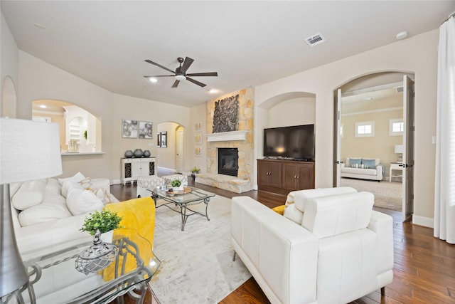21207 Fairhaven Creek Dr, Cypress, TX 77433 - living room featuring a ceiling fan, a stone fireplace, wood finished floors, arched walkways, and visible vents