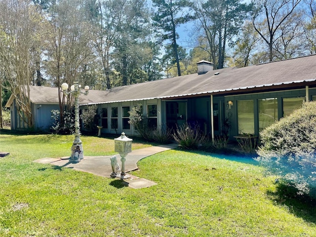 rear view of house with a yard and a chimney
