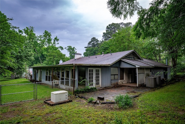 rear view of house featuring a patio, a chimney, a gate, a lawn, and french doors