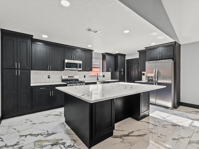 11506 Kirkhollow Dr, Houston, TX 77089 - kitchen featuring appliances with stainless steel finishes, dark cabinets, a kitchen island, recessed lighting, and backsplash