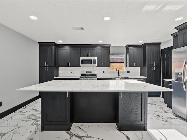11506 Kirkhollow Dr, Houston, TX 77089 - kitchen featuring stainless steel appliances, light marble finish flooring, decorative backsplash, recessed lighting, and dark cabinetry