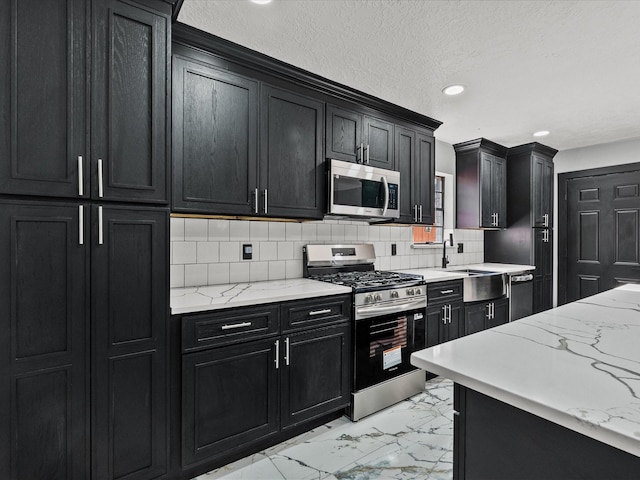 11506 Kirkhollow Dr, Houston, TX 77089 - kitchen featuring appliances with stainless steel finishes, dark cabinetry, light marble finish flooring, recessed lighting, and a sink