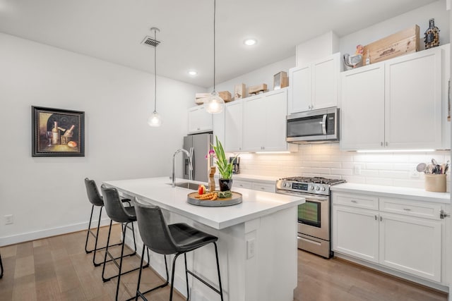 kitchen featuring a breakfast bar, decorative backsplash, stainless steel appliances, and visible vents
