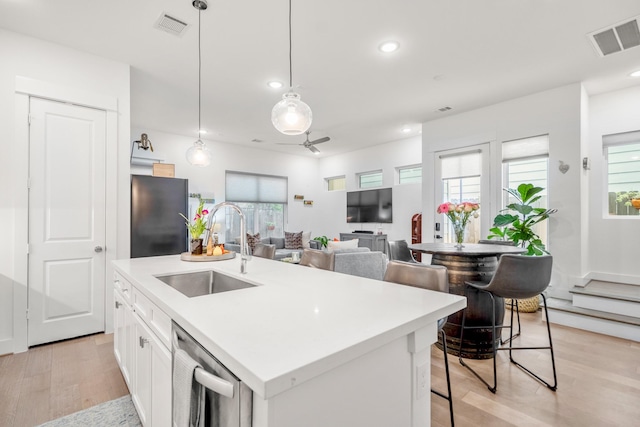 kitchen featuring freestanding refrigerator, visible vents, stainless steel dishwasher, and a sink