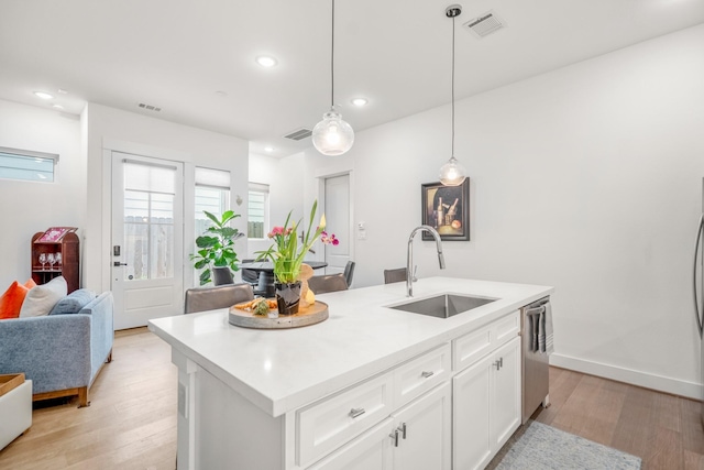 kitchen featuring light wood-style flooring, a sink, open floor plan, visible vents, and dishwasher