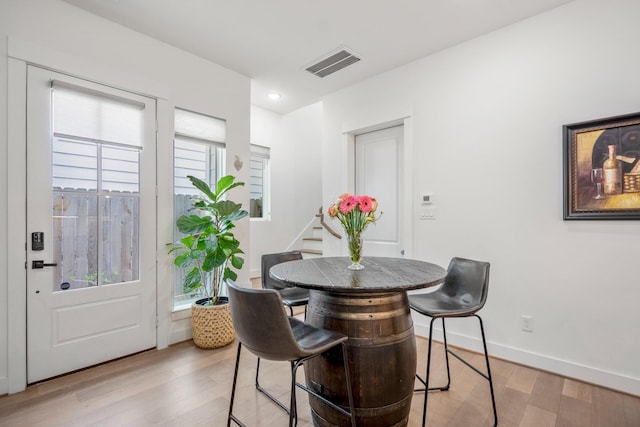 dining area featuring stairway, baseboards, light wood finished floors, and visible vents