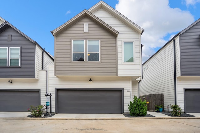 view of front facade with fence, concrete driveway, and a garage