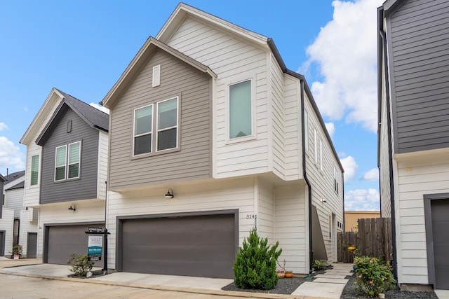 townhome / multi-family property featuring an attached garage, concrete driveway, and fence