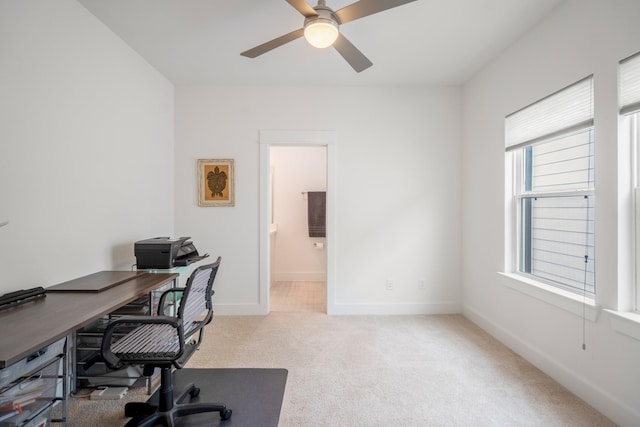 carpeted office space featuring ceiling fan and baseboards