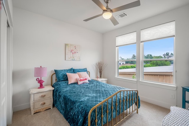carpeted bedroom with visible vents, baseboards, and ceiling fan