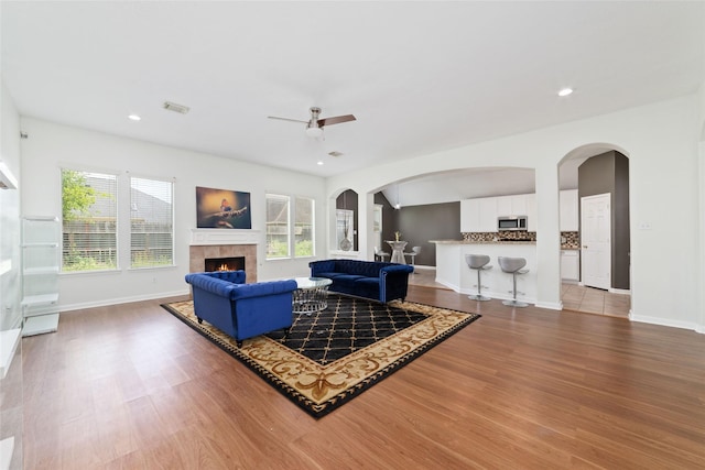 8122 Dune Brook Dr, Pearland, TX 77089 - living area with wood finished floors, ceiling fan, a tile fireplace, arched walkways, and baseboards