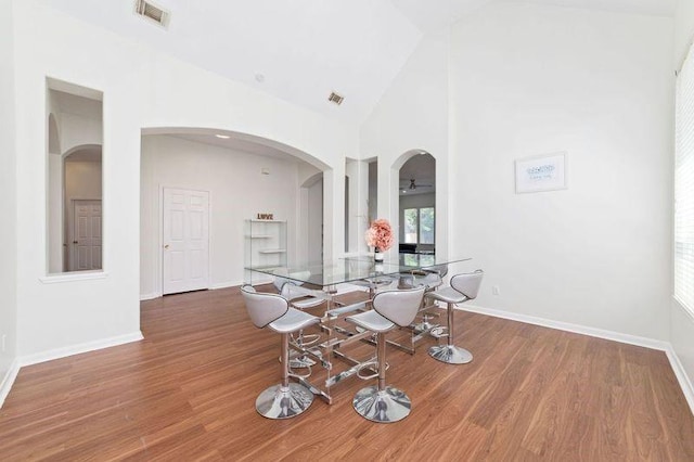 8122 Dune Brook Dr, Pearland, TX 77089 - dining area featuring arched walkways, wood finished floors, high vaulted ceiling, and baseboards