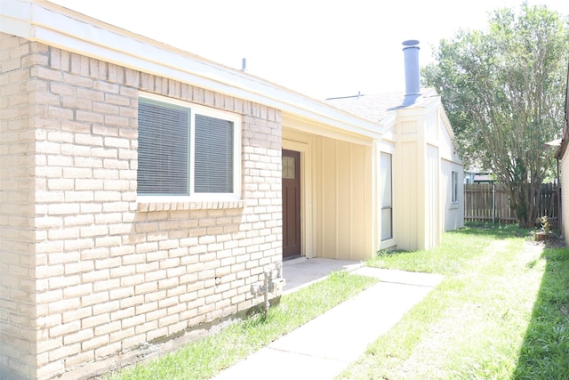 exterior space featuring a front yard, brick siding, board and batten siding, and fence