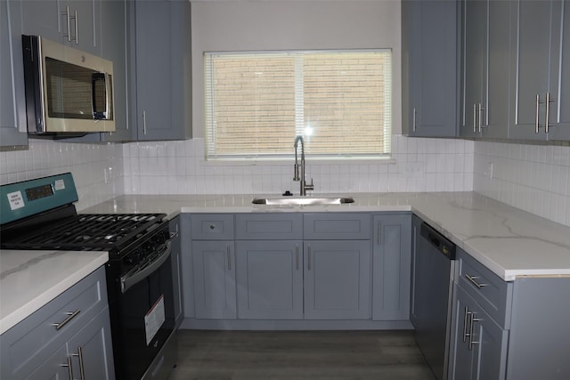 kitchen featuring a sink, tasteful backsplash, appliances with stainless steel finishes, and light stone countertops
