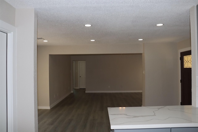 corridor featuring dark wood-type flooring, baseboards, recessed lighting, and a textured ceiling