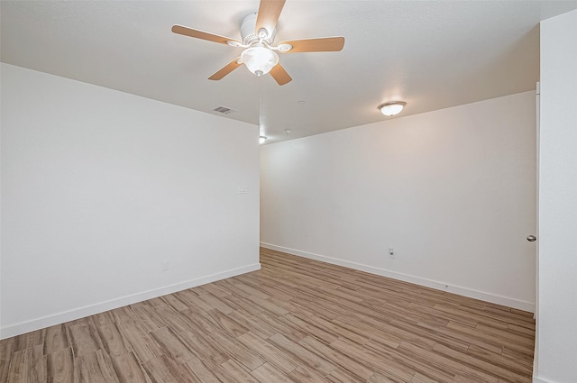 unfurnished room with light wood finished floors, baseboards, a ceiling fan, and visible vents