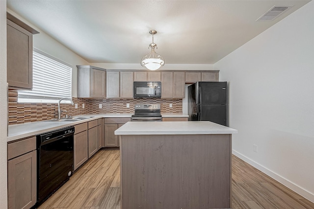 kitchen featuring a center island, black appliances, visible vents, decorative backsplash, and a sink