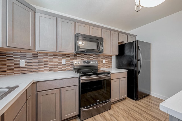 kitchen featuring tasteful backsplash, baseboards, black appliances, and light wood-type flooring