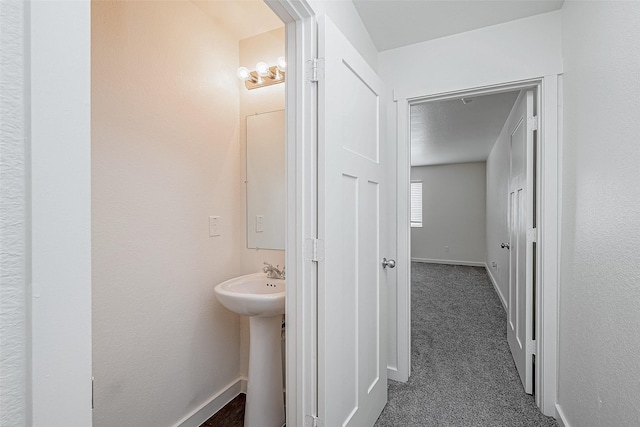 hallway with dark colored carpet and baseboards