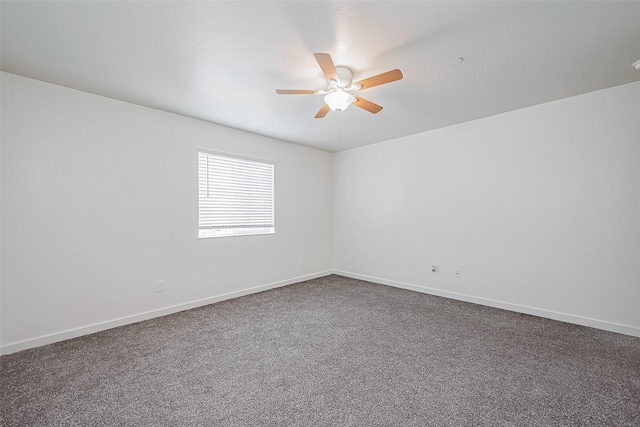spare room with dark carpet, baseboards, and a ceiling fan