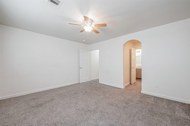 empty room with ceiling fan, arched walkways, visible vents, light carpet, and baseboards