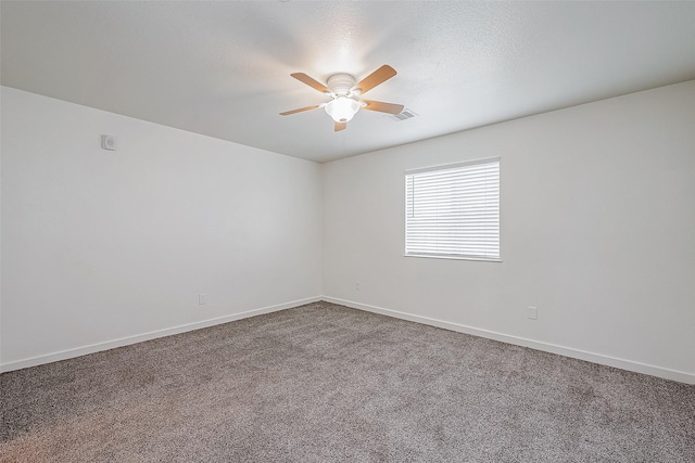 empty room with dark colored carpet, visible vents, baseboards, and ceiling fan