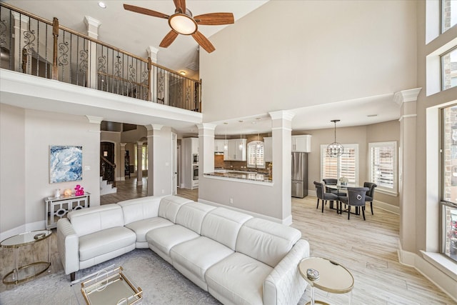 2815 Veneto Ct, League City, TX 77573 - living area with decorative columns, ceiling fan, a high ceiling, light wood-type flooring, and baseboards