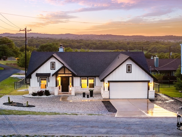 modern farmhouse style home with an attached garage, driveway, board and batten siding, and a shingled roof