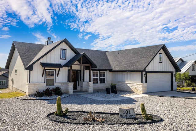 modern farmhouse with an attached garage, a shingled roof, stone siding, and driveway