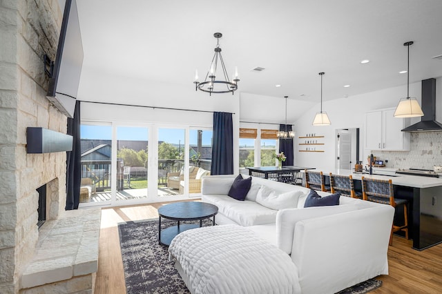 living area with visible vents, a notable chandelier, a fireplace, recessed lighting, and wood finished floors