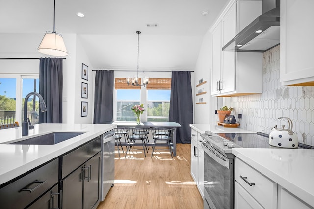kitchen with light wood-type flooring, visible vents, wall chimney exhaust hood, stainless steel appliances, and a sink