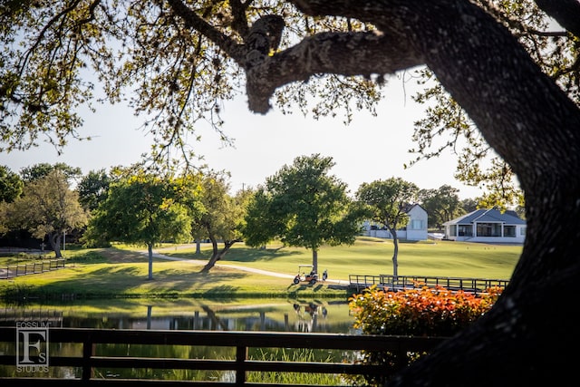 surrounding community featuring a water view, fence, and a yard